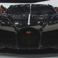 Czarny Bugatti, najdroższe auto na świecie, błyszczy na wystawie, przyciągając wzrok tłumu.