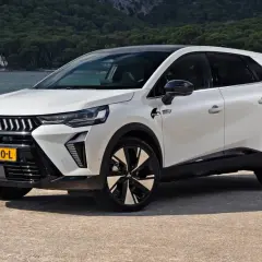 Nowy model Mitsubishi, biały SUV z czarnym dachem, stoi nad wodą. Nowoczesne linie i felgi podkreślają jego dynamiczny charakter.