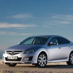 Srebrna Mazda 6 na tle błękitnego nieba i gór.