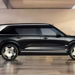Eleganckie, czarne auto na z. z chromowanymi detalami i unikalnymi felgami, prezentuje się w nowoczesnym wnętrzu.
