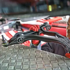 Mechanik w czerwonych rękawiczkach prezentuje nowy wielowahacz do samochodu.