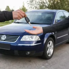 Przekazanie kluczyków do niebieskiego Volkswagena. Dowiedz się, jak zgłosić sprzedaż samochodu i dopełnić formalności.