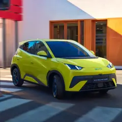 Żółty BYD Dolphin Surf sunie ulicą, niczym mewa nad wodą, w letni dzień.
