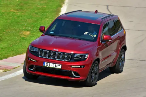 Czerwony Jeep Grand Cherokee z tablicami indywidualnymi "S1 LNY" na torze wyścigowym.