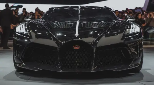 Czarny Bugatti, najdroższe auto na świecie, błyszczy na wystawie, przyciągając wzrok tłumu.