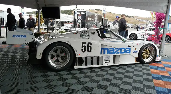 Legenda: Biały samochód wyścigowy Mazda 787B z numerem 56, gotowy do startu.