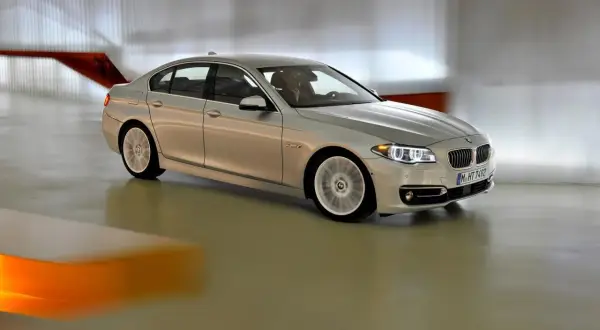 Srebrne bmw f10 lift w ruchu, z rozmytymi kołami, porusza się po nowoczesnym wnętrzu.