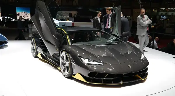 Ciemnoszary Lamborghini z otwartymi drzwiami, z żółtymi akcentami. Zastanawiasz się, ile kosztuje Lamborghini?