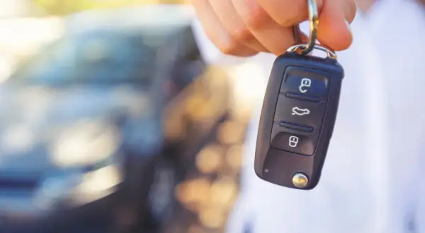 Kluczyk samochodowy z przyciskami. W tle widać zamazany samochód. Czy to immobilizer co to?