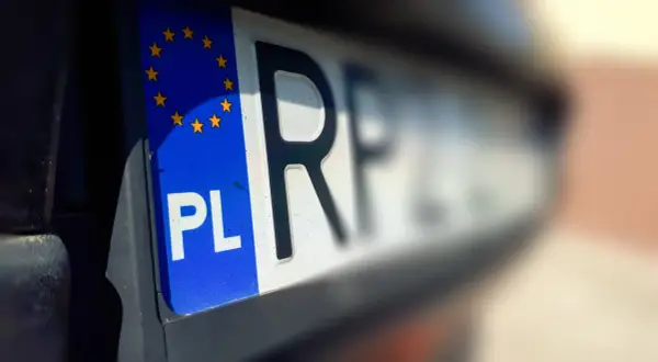 Zbliżenie na polską tablicę rejestracyjną z symbolem Unii Europejskiej. Litery "PL" i fragment numeru wskazują na bsi rejestracja.