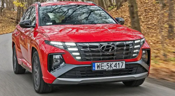 Czerwony Hyundai Tucson N Line w ruchu, z widoczną długością maski i grillem.