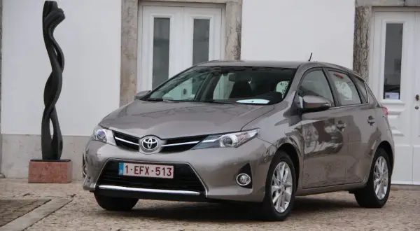 Szary Toyota Auris 1.6 benzyna zaparkowany obok rzeźby.