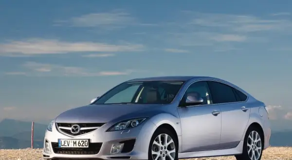 Srebrna Mazda 6 na tle błękitnego nieba i gór.