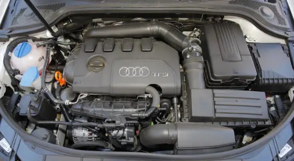 Widok komory silnika z widocznym silnikiem 2.0 TFSI Audi, zbiornikiem płynu chłodniczego i filtrem powietrza.