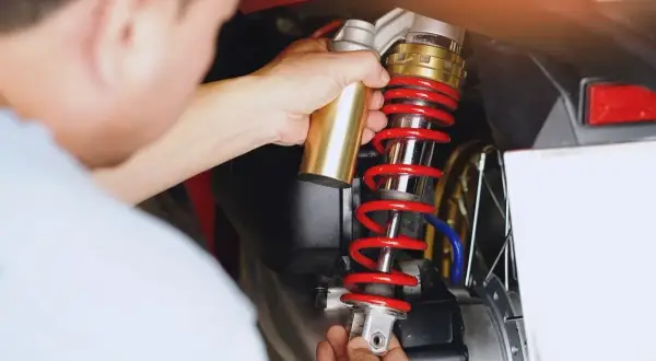 Mechanik wymienia amortyzator w motocyklu. Sprawdź wymiana amortyzatorów cena, by zadbać o bezpieczeństwo jazdy.
