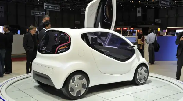 Białe, futurystyczne auto, które mogłoby być najtańszym autem na świecie, prezentowane na wystawie.