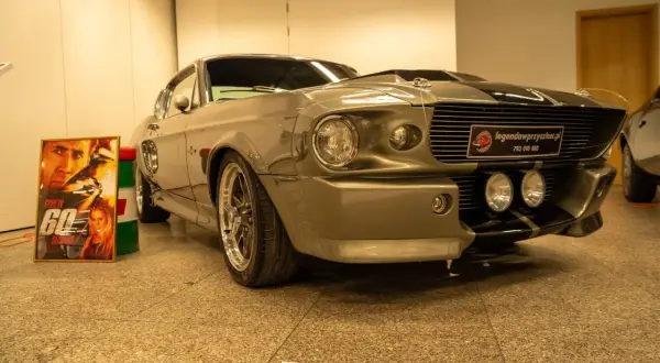 Szary Ford Mustang „Eleanor” z filmu „60 sekund” obok plakatu z Nicolasem Cage'em.