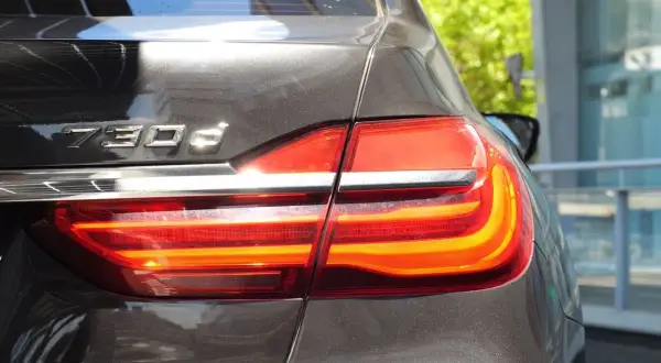 Tylna część lśniącego BMW 730d z włączonymi światłami stopu.
