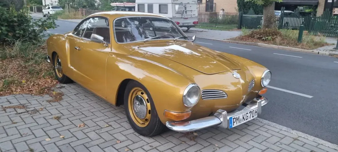 Złoty Karmann Ghia, klasyk z lat 60., lśni na tle ulicy.