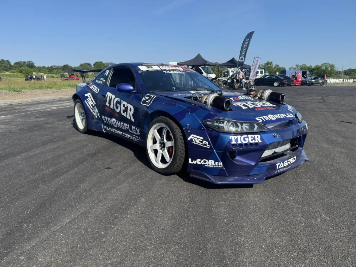 Niebieski samochód driftowy s15 z podwójnymi turbosprężarkami i licznymi sponsorami, gotowy do akcji.