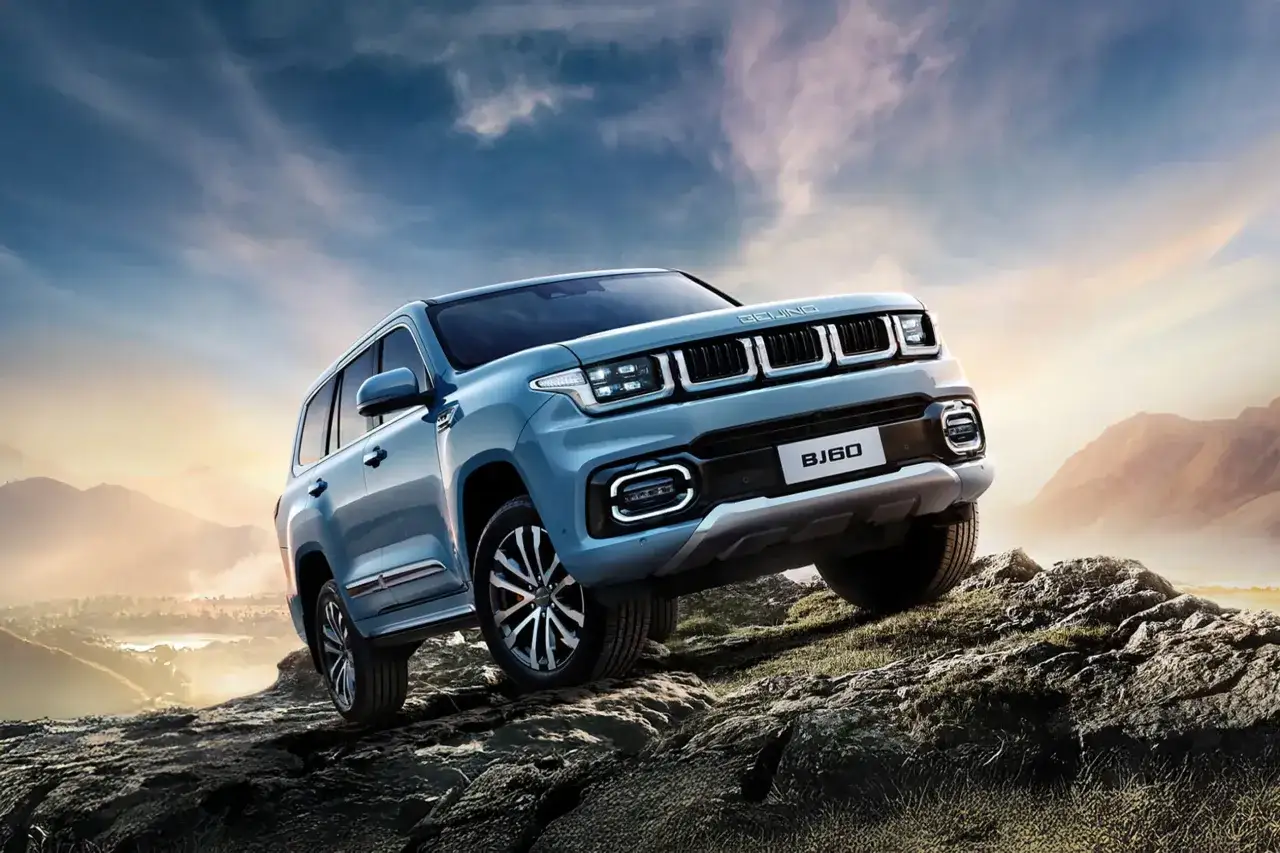 Niebieskie beijing auto BJ60 pokonuje skalisty teren na tle gór i zachodzącego słońca.