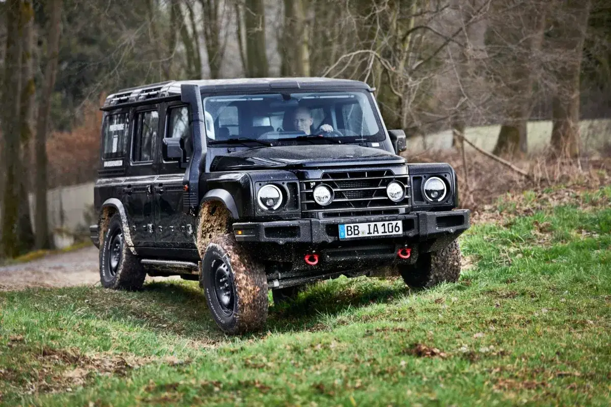 Czarny INEOS Grenadier, ubrudzony błotem po off-roadowej przejażdżce, gotowy na nowe wyzwania. Sprawdź, jaka jest jego cena!
