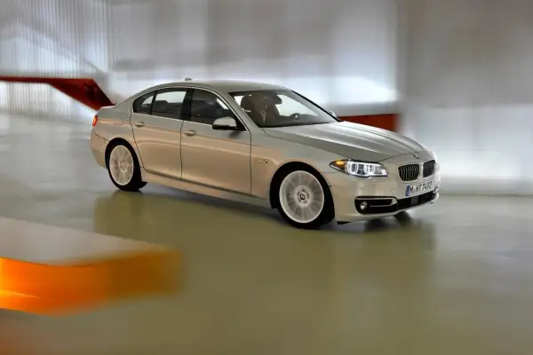 Srebrne bmw f10 lift w ruchu, z rozmytymi kołami, porusza się po nowoczesnym wnętrzu.