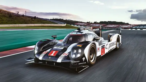 Porsche 919 Hybrid pędzi po torze wyścigowym, oznaczony numerem 1, w barwach czarno-białych z flagą Niemiec.