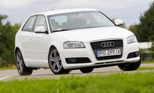 Białe Audi A3 8P 1.6 MPI na zakręcie. Kierowca w środku. Opinie o tym modelu są różne, ale wygląd zachwyca.