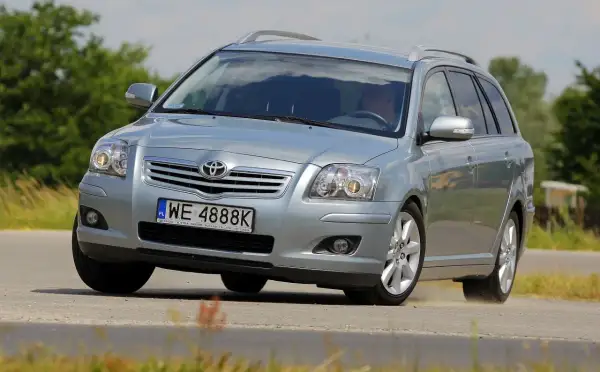 Srebrny kombi Toyota Avensis T25 z polskimi tablicami WE 4888K pokonuje zakręt na drodze, unosząc lekki pył.