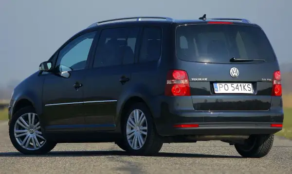 Ciemny Volkswagen Touran 2.0 TDI na drodze, widok z tyłu i boku.