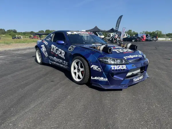 Niebieski samochód driftowy s15 z podwójnymi turbosprężarkami i licznymi sponsorami, gotowy do akcji.